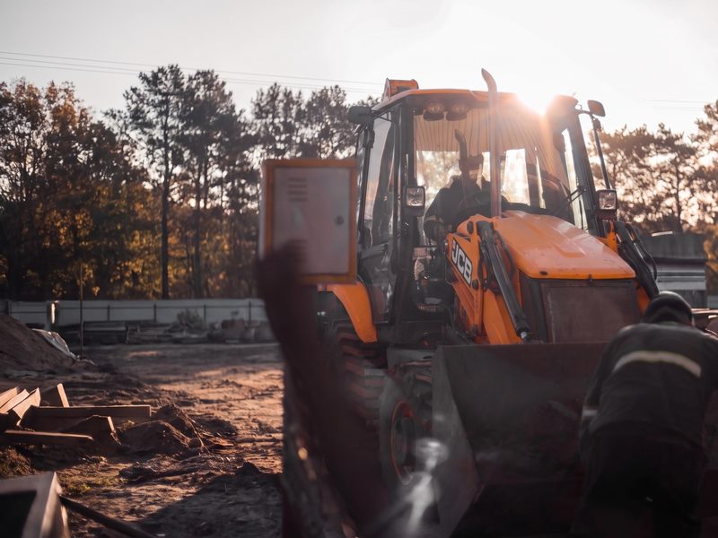 Retroescavadeira JCB da Brava em canteiro de obra ao entardecer